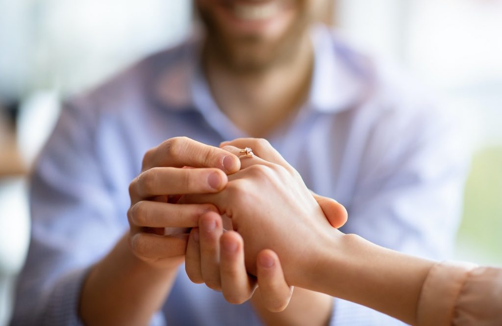 We are getting married. Happy fiance holding his future wife's hand with engagement ring on